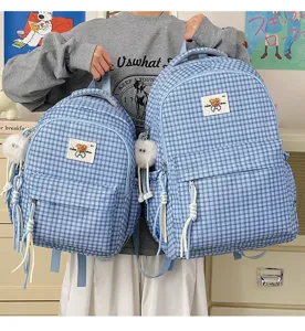 Cute blue plaid backpack detail featuring fluffy pendant and adorable bear patch, ins style.