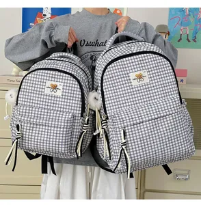 Cute black and white plaid backpack with bear patch and plush pom pom pendant for daily school use.