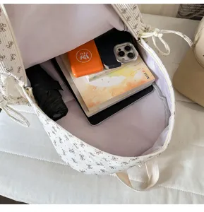 Detail shot showing the interior capacity of the white bow print school backpack with items.