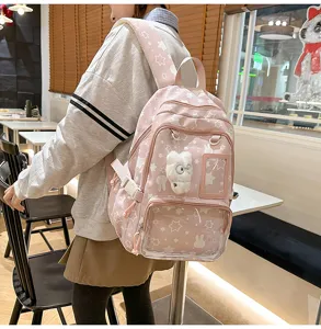 Cute pink school backpack for girls with star patterns, clear front pocket and plush charm.