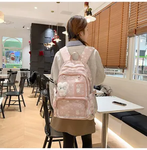 Detailed view of pink star print student backpack featuring clear front pocket and plush pendant.