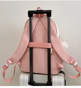 Detail view of pink cute school backpack with luggage strap and fluffy ball charm, travel bag.