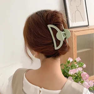 Detail view of a matte hollow hair claw clip worn on the back of the head, elegant daily accessory.
