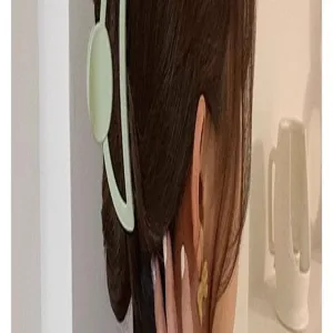 Detailed side view of a stylish light green crescent hair claw clip worn on brown hair.
