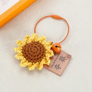 Close-up of handmade crochet sunflower keychain with orange cable ring and cute bell pendant.