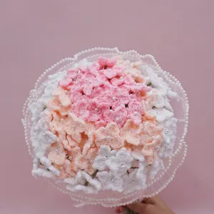 Handcrafted crochet flower bouquet close up, soft pink and white yarn floral design with pearls.