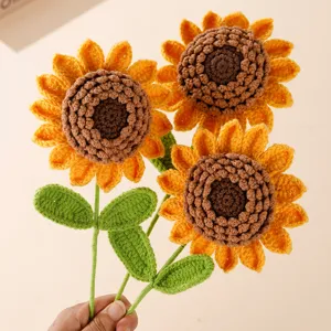 Detail view of handmade crocheted sunflower bouquet, showing textured petals and green leaves.