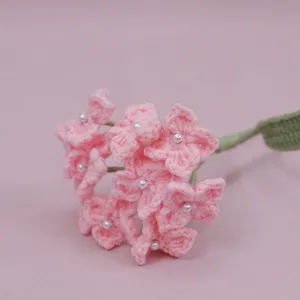 Handmade crochet pink hydrangea flower detail close-up, wool knit artificial floral decor piece.