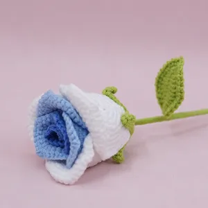 Detailed close-up of handmade crochet blue and white gradient rose flower with green leaf.