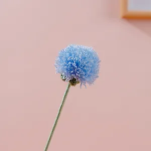 Dettaglio fiore tarassaco lavorato a maglia, pompon blu decorazione floreale in lana.