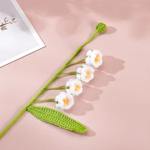 Close-up detail of handcrafted crochet lily of the valley flower branch, soft yarn texture.