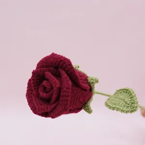 Close-up of handmade crochet red rose flower, detailed yarn texture, elegant home decor detail.
