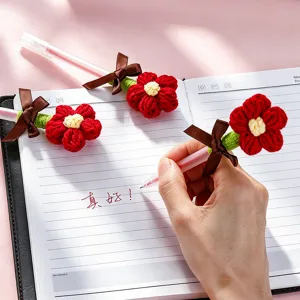 Handmade crochet flower gel pen detail shot, cute red floral design with bow ribbon for gift writing.