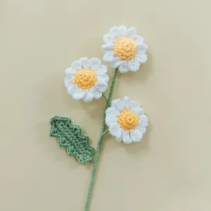 Detailed view of hand-crocheted daisy flower with white petals, yellow center and green stem.