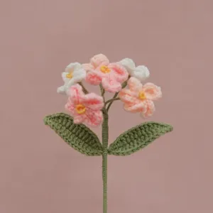 Dettaglio fiore non-ti-scordar-di-me all'uncinetto fatto a mano, trama lana e toni pastello.