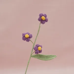 Detailed view of handmade crochet purple puff flower branch, delicate stem and green leaf.