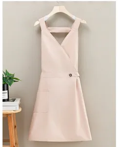 Detail view of pink waterproof cooking apron with cross straps and pocket for kitchen work.