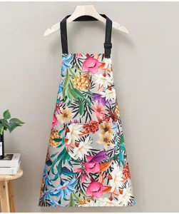 Floral print kitchen apron detail, waterproof fabric with adjustable black straps and pocket.