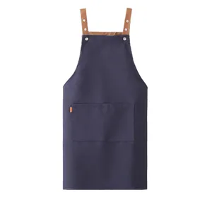 Grembiule da cucina in tela blu scuro con spallacci marroni, tasche e rivetti metallici.