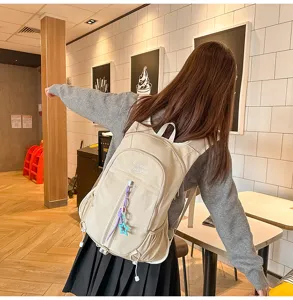 Detailed shot showing the beige canvas backpack worn by model, casual outdoor travel bag.