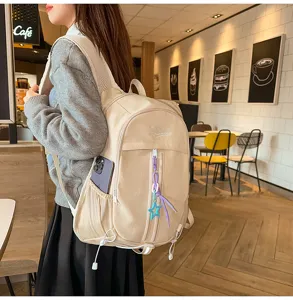 Detailed view of the casual beige backpack featuring multiple pockets and stylish charms.