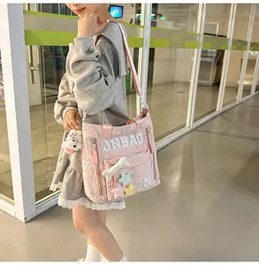 Pink canvas shoulder bag detail view with cute plush bone and star accessories on the front.