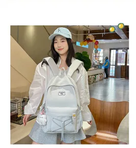 White student backpack with elastic cord front pocket and cute pendant for daily school use.