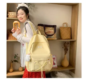 Detailed lifestyle view of a bright yellow student backpack featuring cute front pocket and plush pendant.