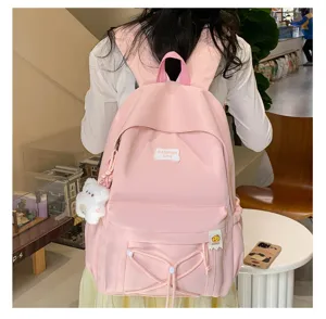 Pink student backpack detail view, showcasing cute bear pendant and front pocket design.