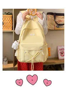 Candy color student backpack detail highlighting front bow drawstring and cute plush pendant.