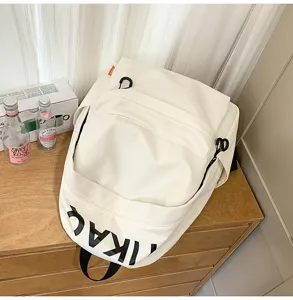 Detailed view of white canvas casual backpack with bold letter print on wooden surface.