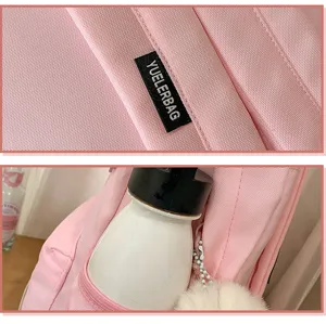 Pink canvas backpack detail showing brand logo patch and side pocket with water bottle.