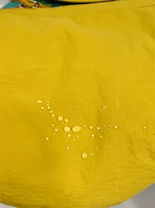 Détail du tissu du sac bandoulière jaune, gros plan sur la matière déperlante.
