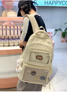 Detailed view of large capacity canvas backpack with transparent pocket and cute badges.