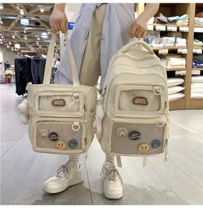 Detail shot of beige canvas ita backpack and tote bag with clear window and cute badges.