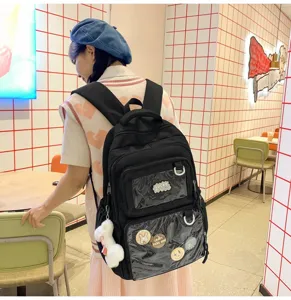 Detail view of black ita backpack with clear pockets and cute badges in cafe setting.