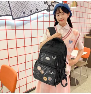Detail view of the black college style backpack featuring transparent front pockets and cute badges.