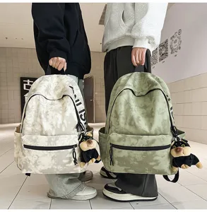 Detail view of the American retro tie-dye canvas backpack with cute plush dog pendant.