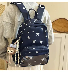 Vista detallada de la mochila azul con estrellas, bolsillo frontal transparente y un lindo dije.