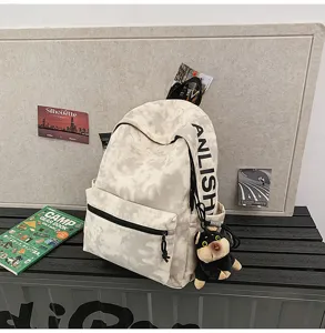 Canvas casual backpack detail view featuring tie-dye pattern, side letter print and cute pendant.