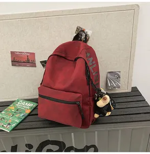 Detailed view of retro red canvas backpack with large capacity and cute dog plush pendant.