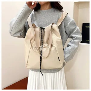 Beige canvas drawstring backpack detail, casual commute shoulder bag with top handle and capacity.
