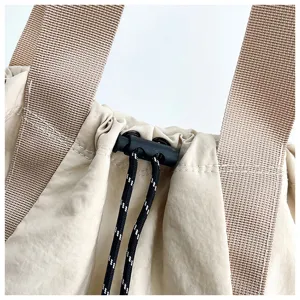 Canvas drawstring bag detail showing adjustable cord lock and wide shoulder straps close up.