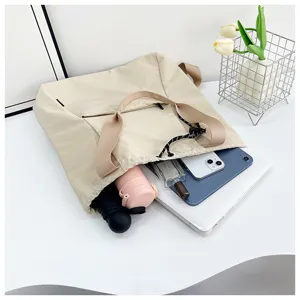 Large capacity beige drawstring canvas tote bag detail, perfect for commuting and daily use.