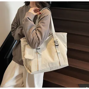 Detail view of the large capacity beige canvas tote bag with shoulder straps and side pocket.