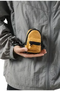 Vista de cerca detallada del mini monedero de mochila amarilla sostenido en la mano con cremallera.