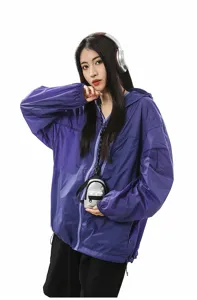 Vista detallada de un mini bolso de cuello plateado usado con una sudadera morada.
