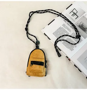 Detalle de mini mochila monedero, bolso amarillo con correa para llaves, tarjetas y auriculares.