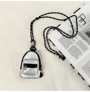 Mini mochila plateada metalizada para el cuello, un pequeño monedero con cordón.