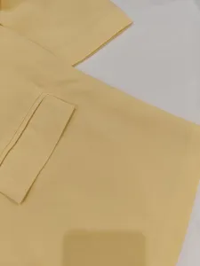 Close-up detail of light yellow women blazer pocket design, premium summer fabric texture.